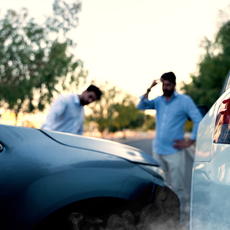 Two people standing beside their crashed car, looking shocked and distressed after an accident