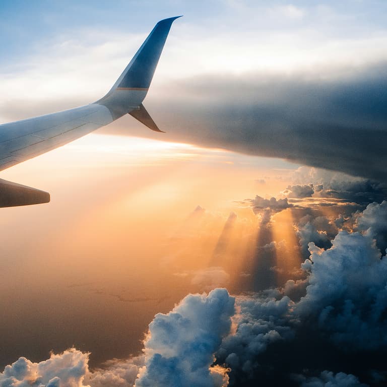 View from an airplane window flying above the clouds, showcasing a scenic sky